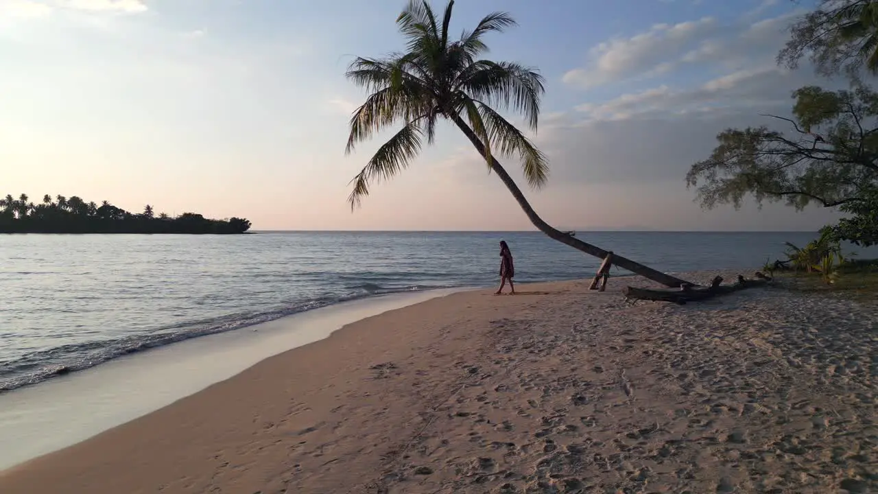 Yoga girl stands up under palm trees on dream beach