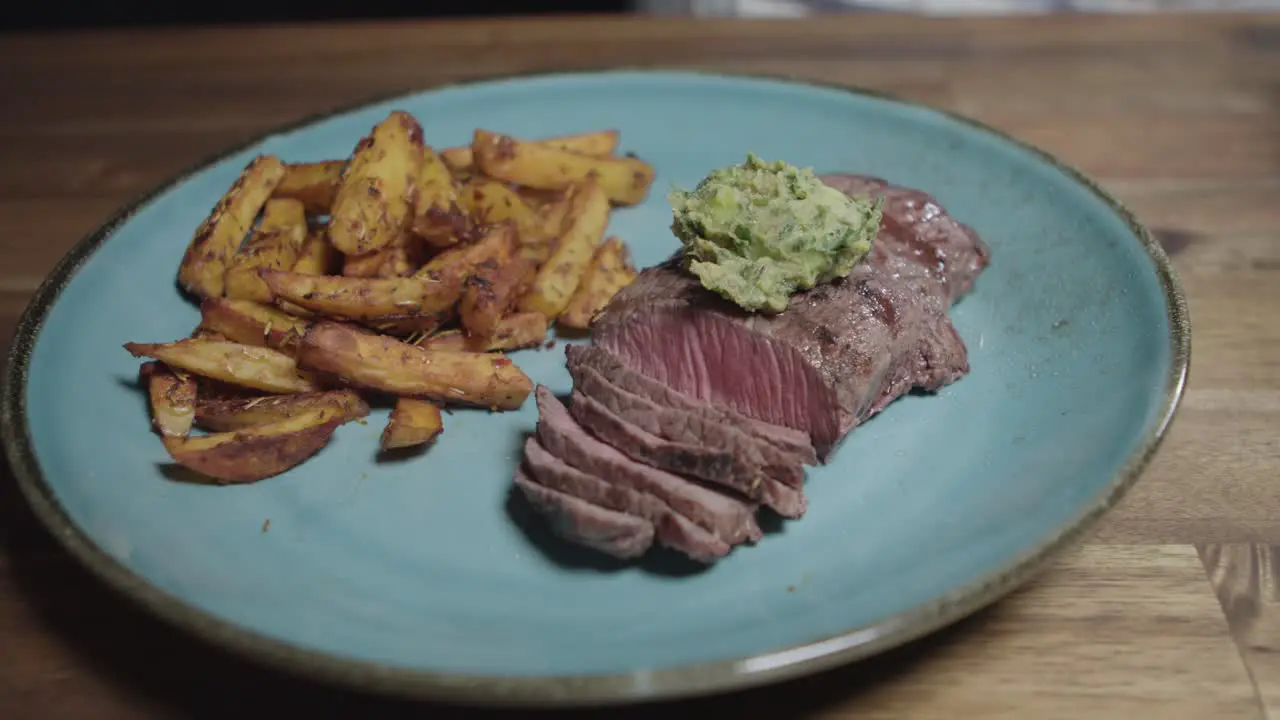 Chef puts cafe en paris butter on slices of meat on a plate accompanied by french fries argentine food