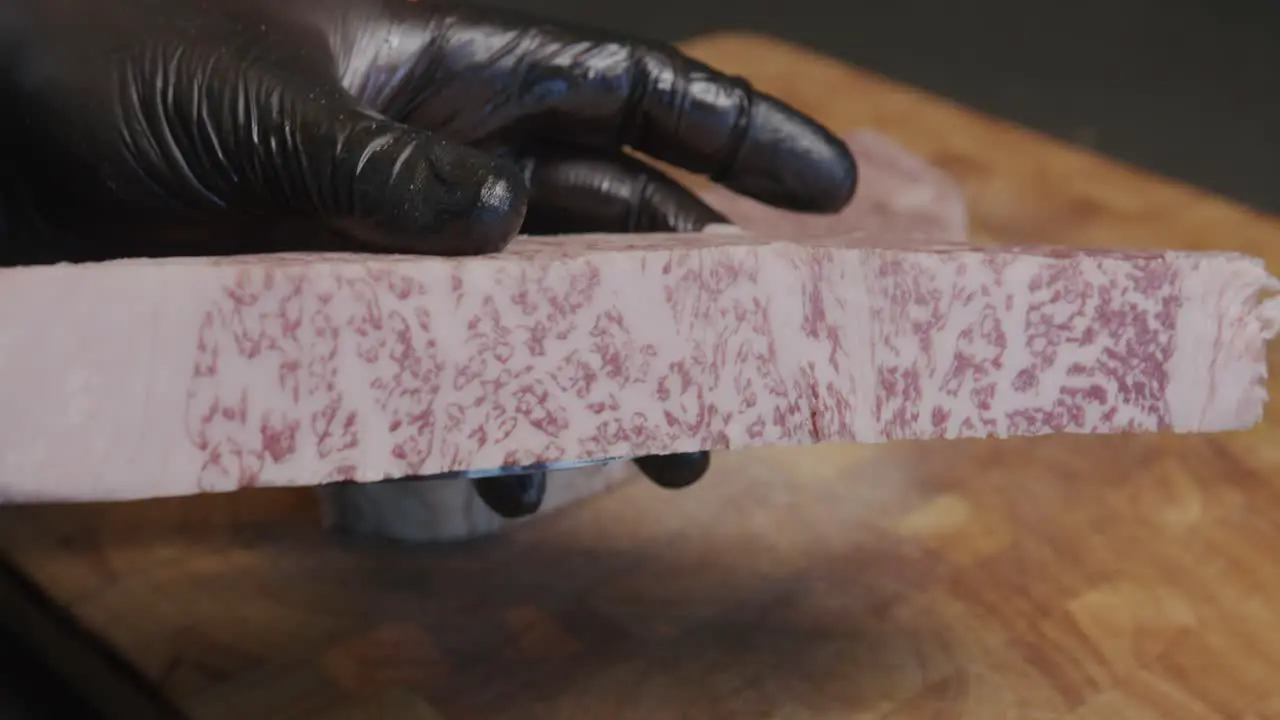 A chef skillfully slices Wagyu beef and presents the cut to the camera showcasing its exceptional quality