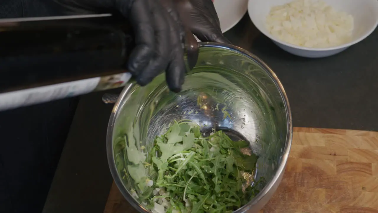 Oil is poured delicately into a bowl of fresh arugula enhancing the salad's flavor