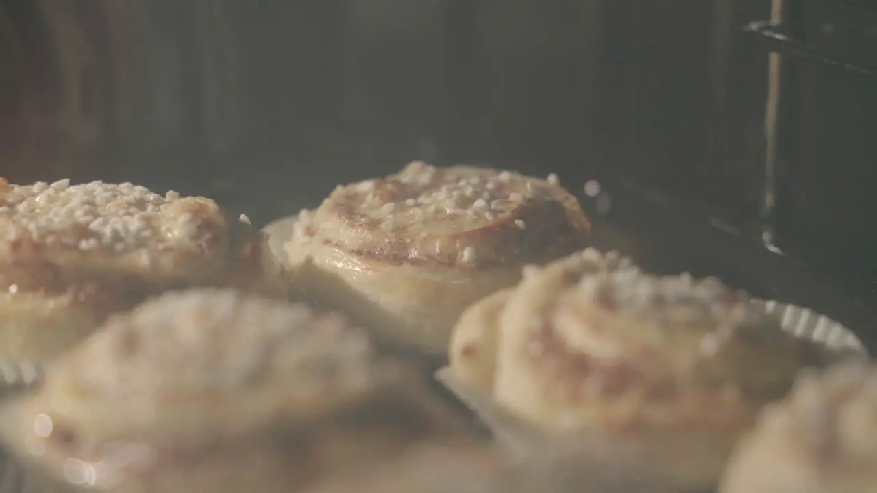 Close up of cinnamon buns getting baked in an oven with buns in the foreground