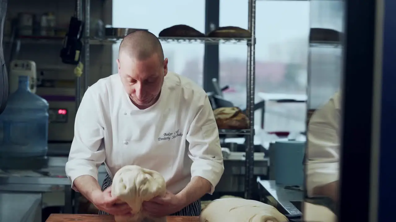 The baker kneads the wet bread dough