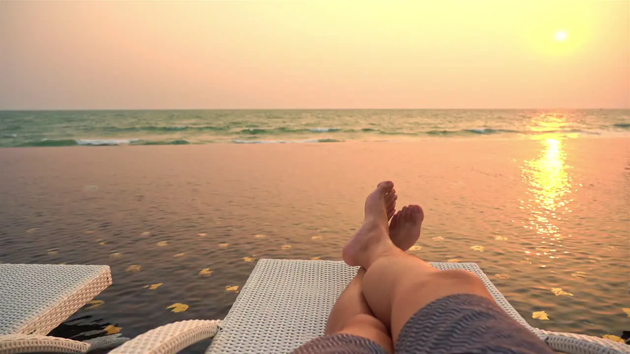 Personal POV of Male Laying on Infinity Pool Bed Watching Sea Waves Under Sun