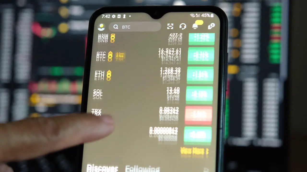 hand scrolling Binance app with candle sticks in the background