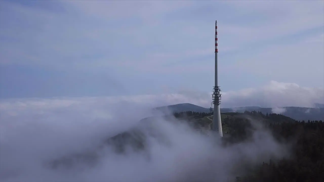 Timelapse Aerial shot of big broadcasting tower stinging through the cloud sitting on the black forest mountain Hornisgrinde a bright day in Autumn