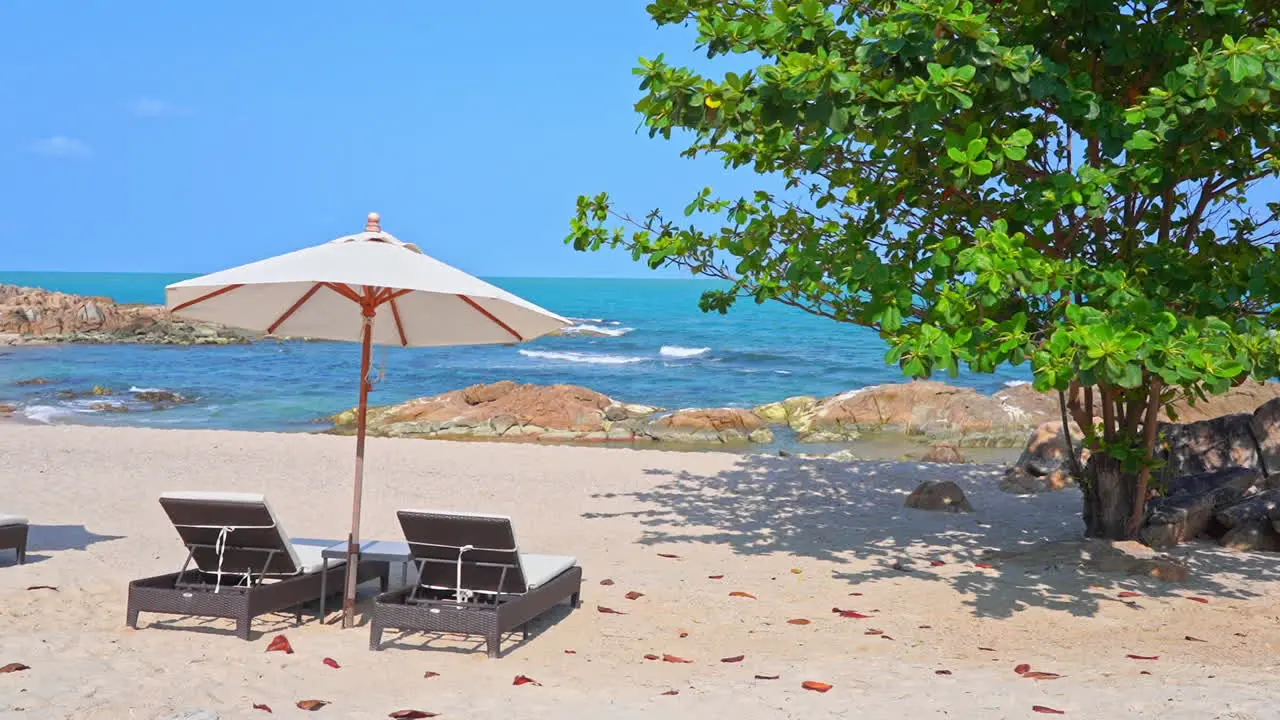 Sun umbrella and two deckchairs on rocky beach with sea in background