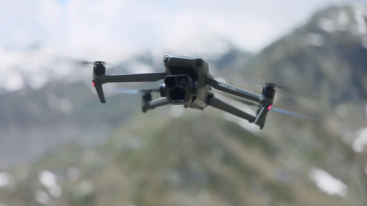 DJI Mavic 3 Pro Hovering And Swaying In Air With Bokeh Background Of Snow Capped Mountains In Switzerland