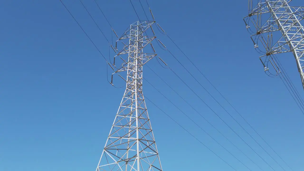 Electricity transformer tower on a blue sky backdrop with electric cable wires lines