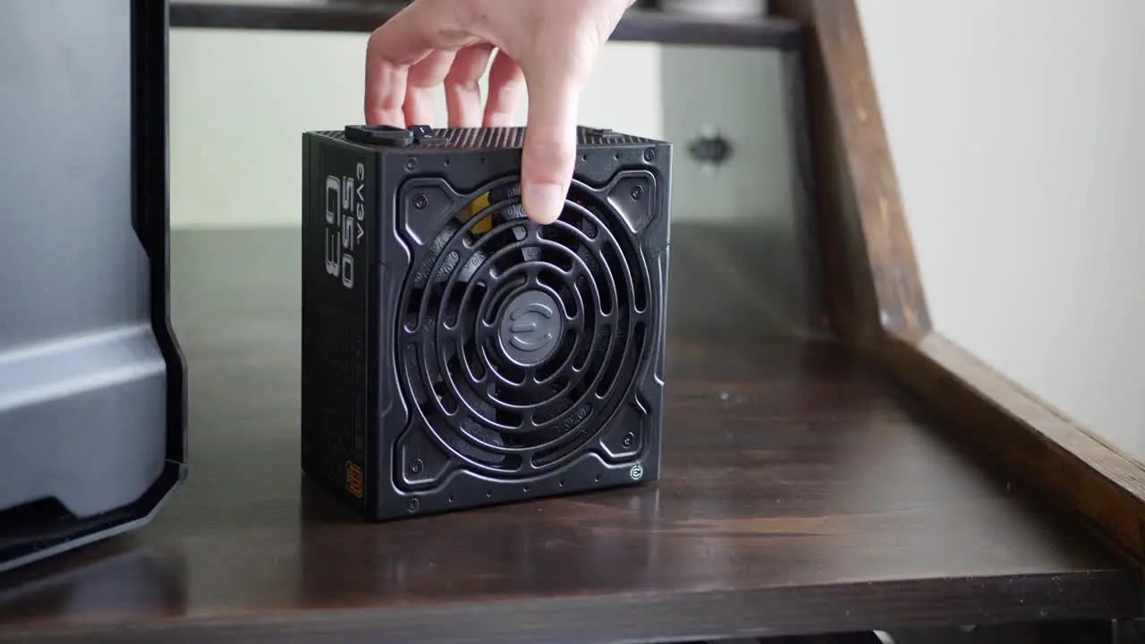 A computer repair technician unboxing an EVGA Gold rated power supply next to a pc case during a gaming build assembly