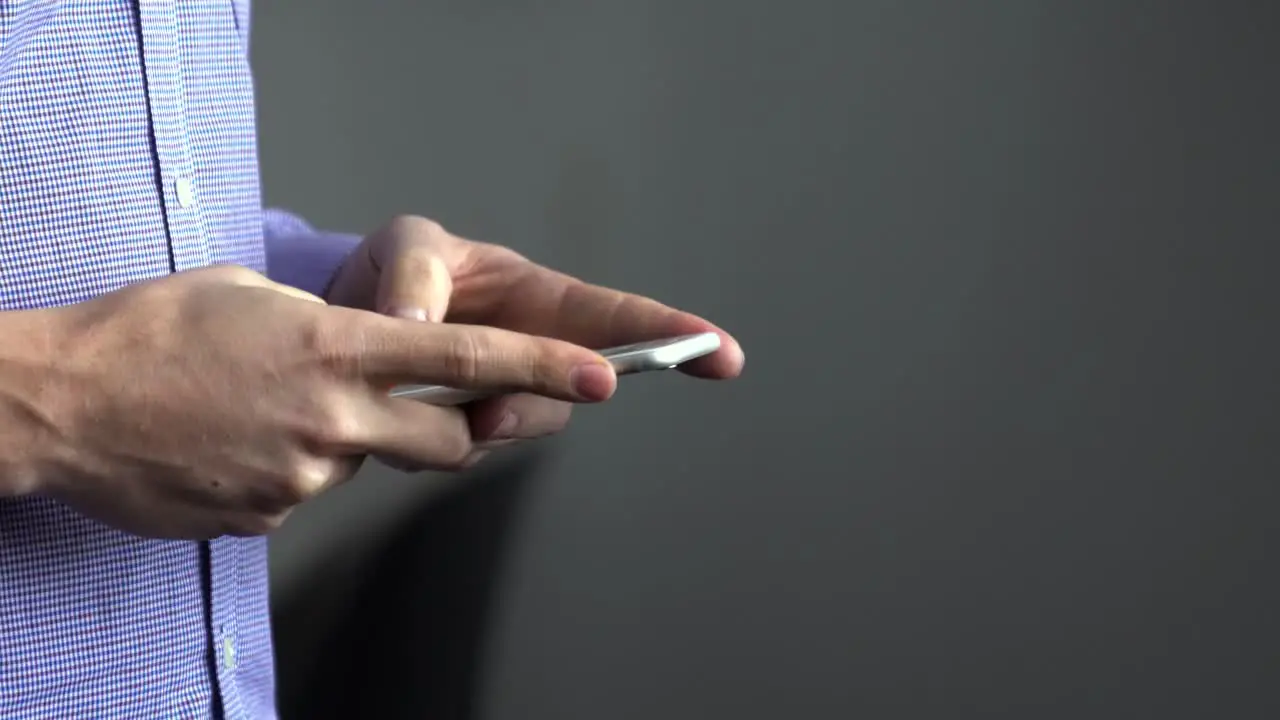 Side view close up shot of a man typing using cell phone in hands