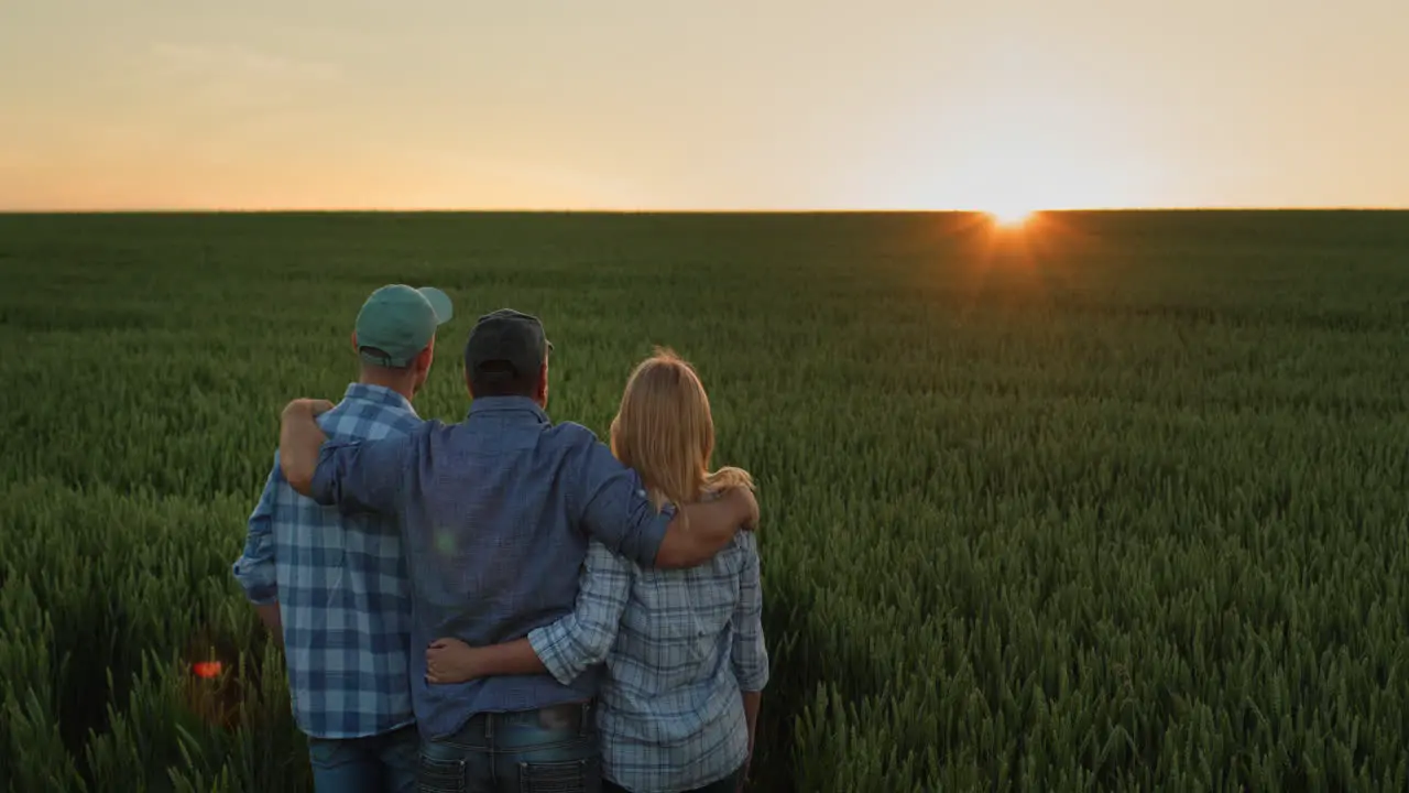 A friendly family of farmers admiring the sunset over a field of wheat