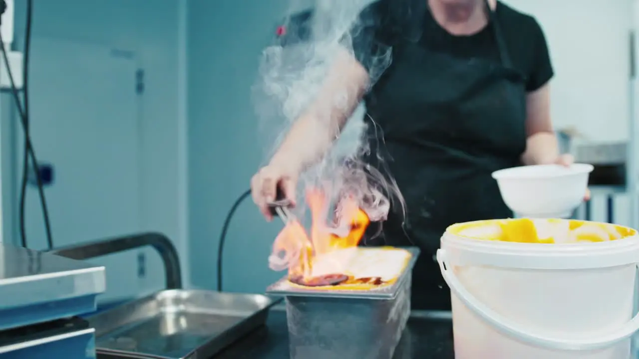 Lady cooking ice cream flambe in an industrial kitchen