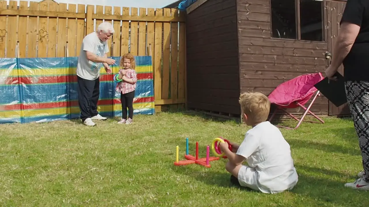 Grandparents having fun playing games with grandchildren in the backgarden during summertime