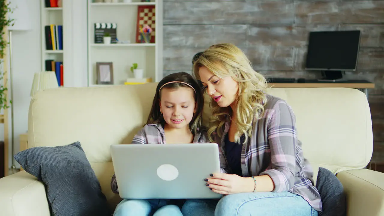 Little girl and her mother sitting on the couch in living room