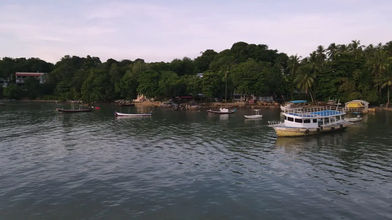 Drone aerial slow move backwards with Thai boats over tropical blue water