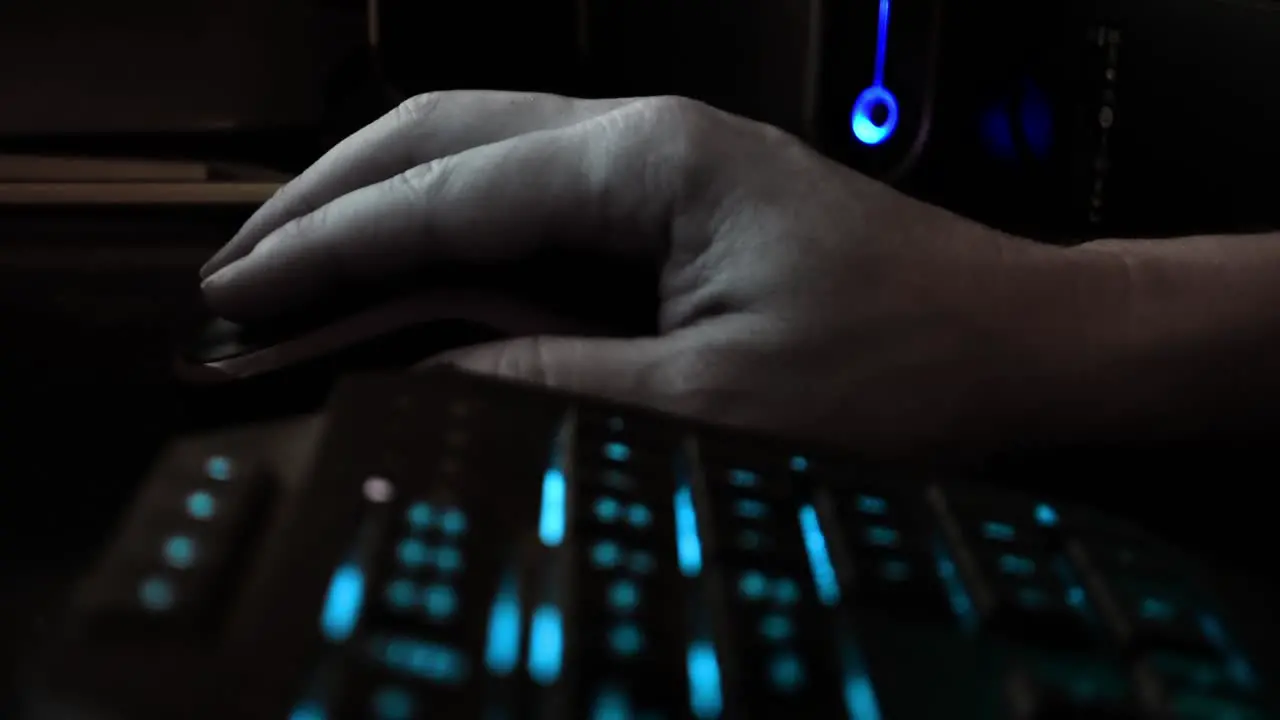 Close up on the hand of a hacker using a computer mouse dark office