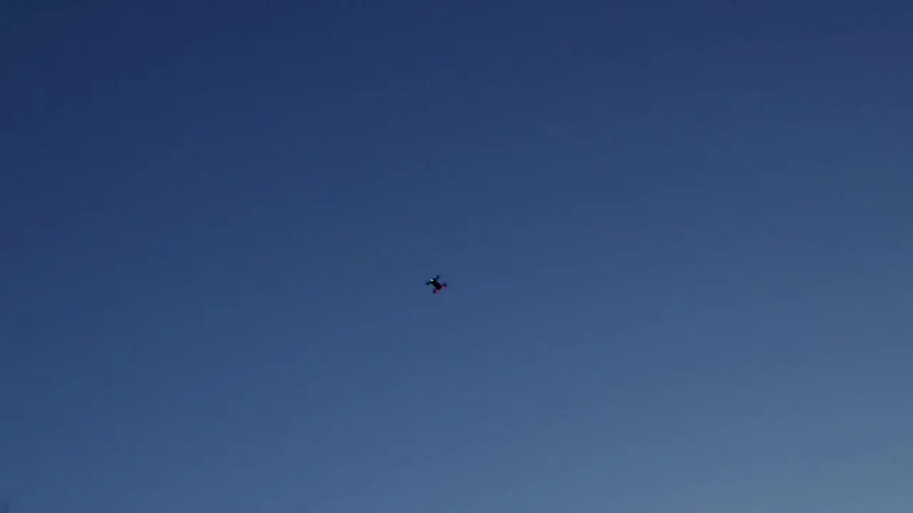 Drone flying isolated as a silhouette in a blue sky