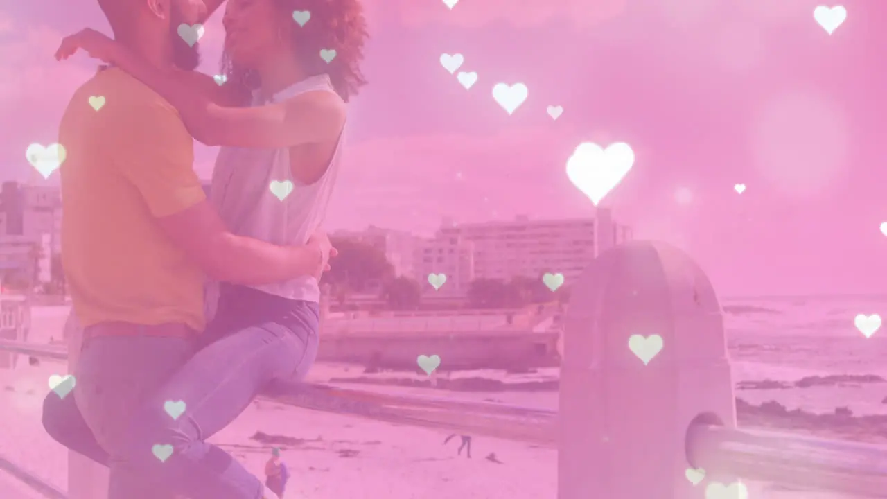 Animation of heart icons over biracial couple at beach