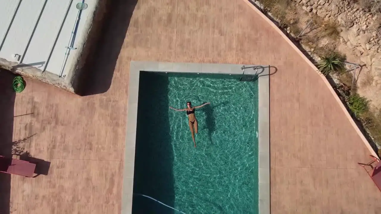 Aerial view of girl relaxing in a swimming pool in Spain