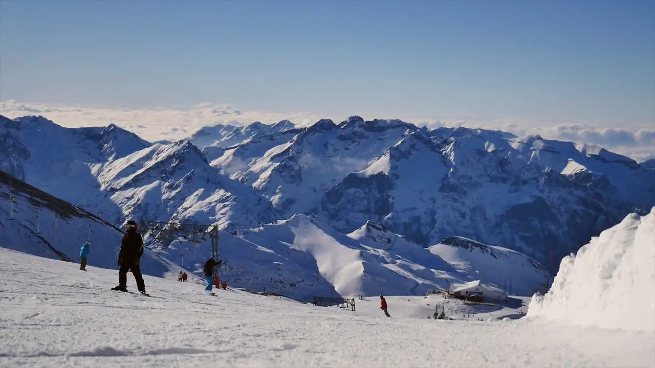 group of snowboarders passing by the camera going down a ski slope with mountain background on a sunny day on a glacier