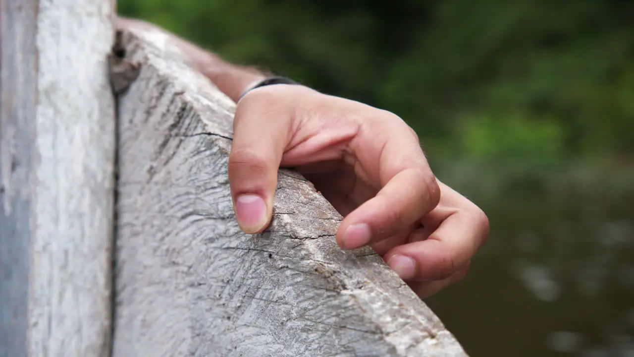 Close up of hand holding wooden boat travelling up the Amazon on an overcast day