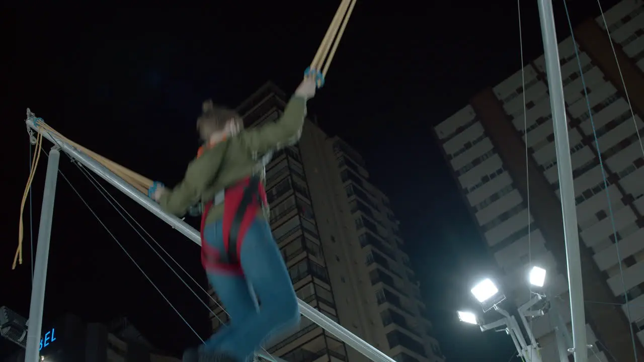 Boy having fun on bungee trampoline in amusement park at night