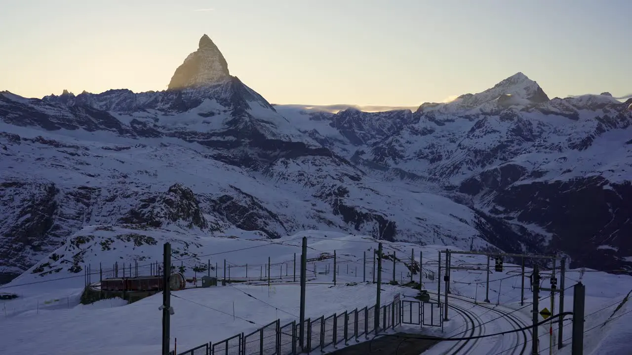 Gornergrat mountain railway train moves to its final stop at Gornergrat with impressive views of the Matterhorn mountain in the background at sunset