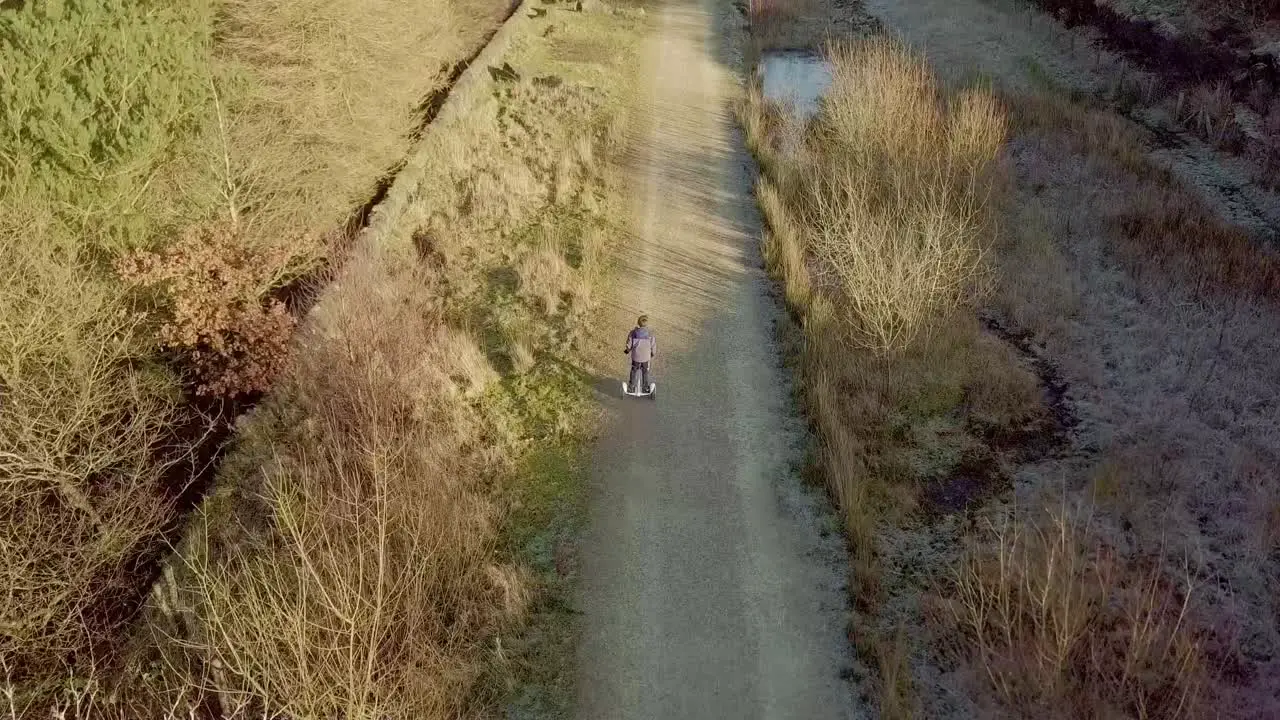 Young boy riding down a country pathway on a hoverboard