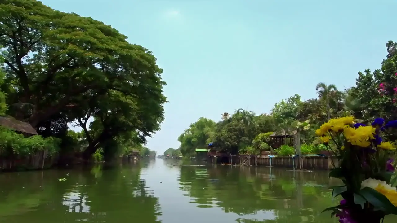 View looking out from the front of a boat moving slowly along on a canal in Thailand