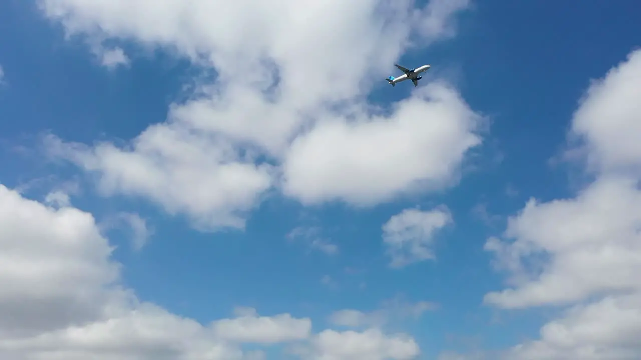 Plane approaching airport landing against blue sky clouds panning