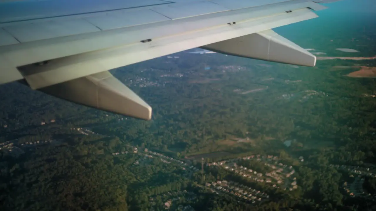 the view from behind an ariplane wing as it flies over a forested area