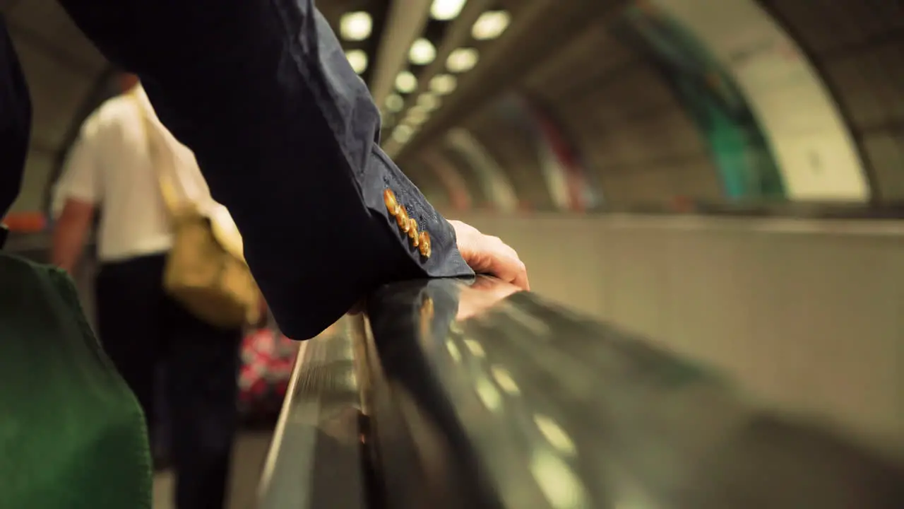 Traveling on a horizontal escalator on the London Underground suit sleeve and hand visible of male rider