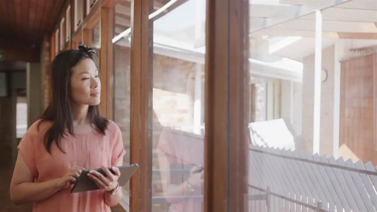 Happy asian female teacher with tablet in school corridor at elementary school copy space