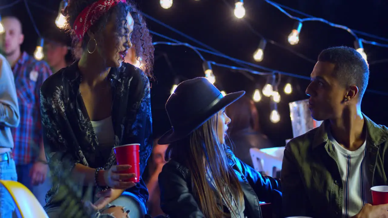 Happy Joyful Multiethnic Group Of Young Friends Sitting Chatting Joking And Laughing At Night On The Rooftop Party