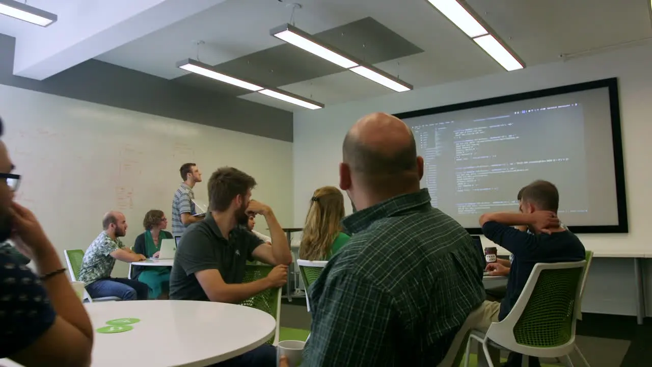 Room of employees listening to a software presentation in a modern office