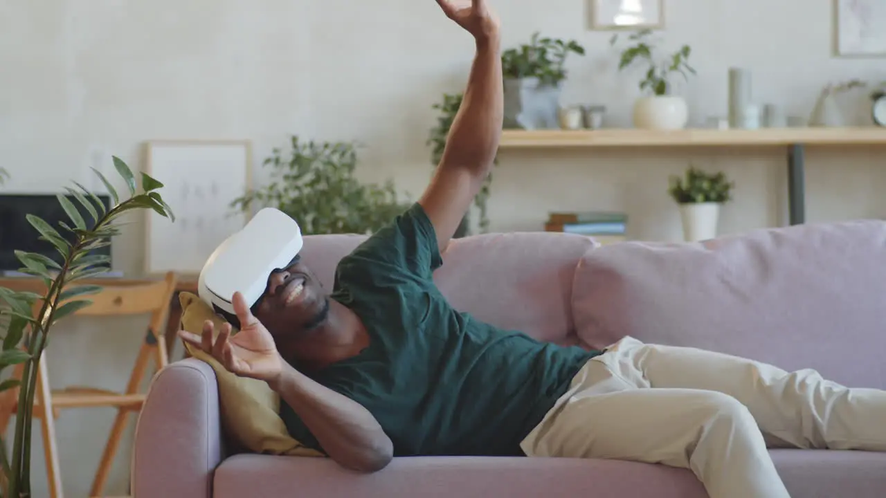 Excited African American Man Lying on Sofa and Using VR Headset