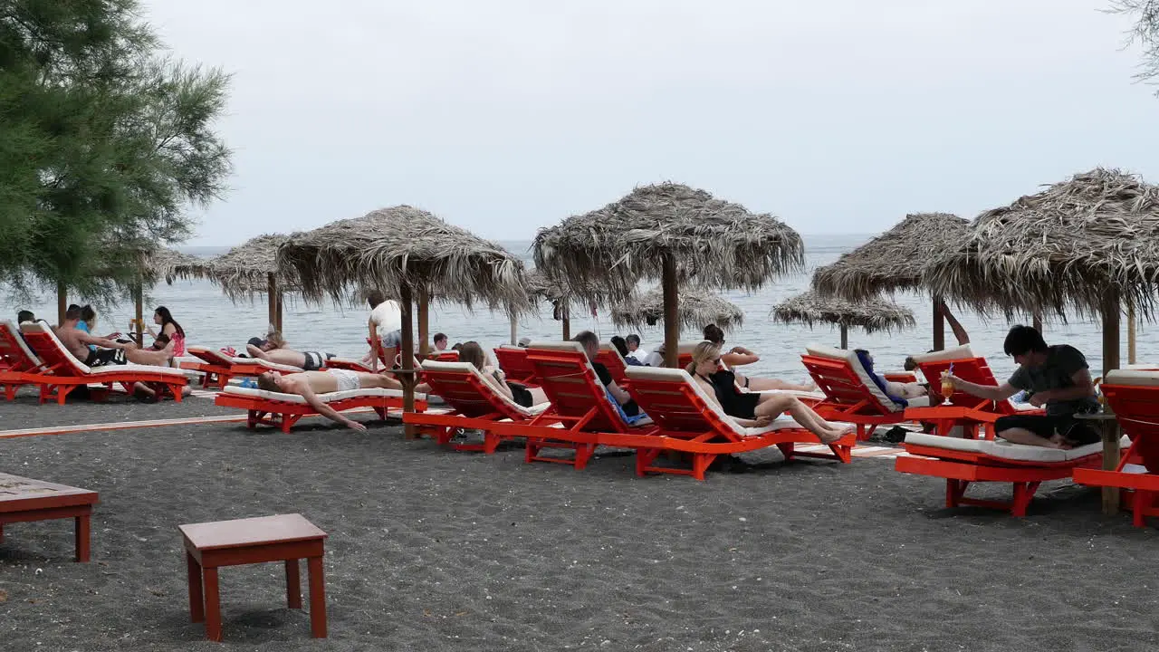 Greece Santorini Perissa Tourists Resting On Black Sand Beach