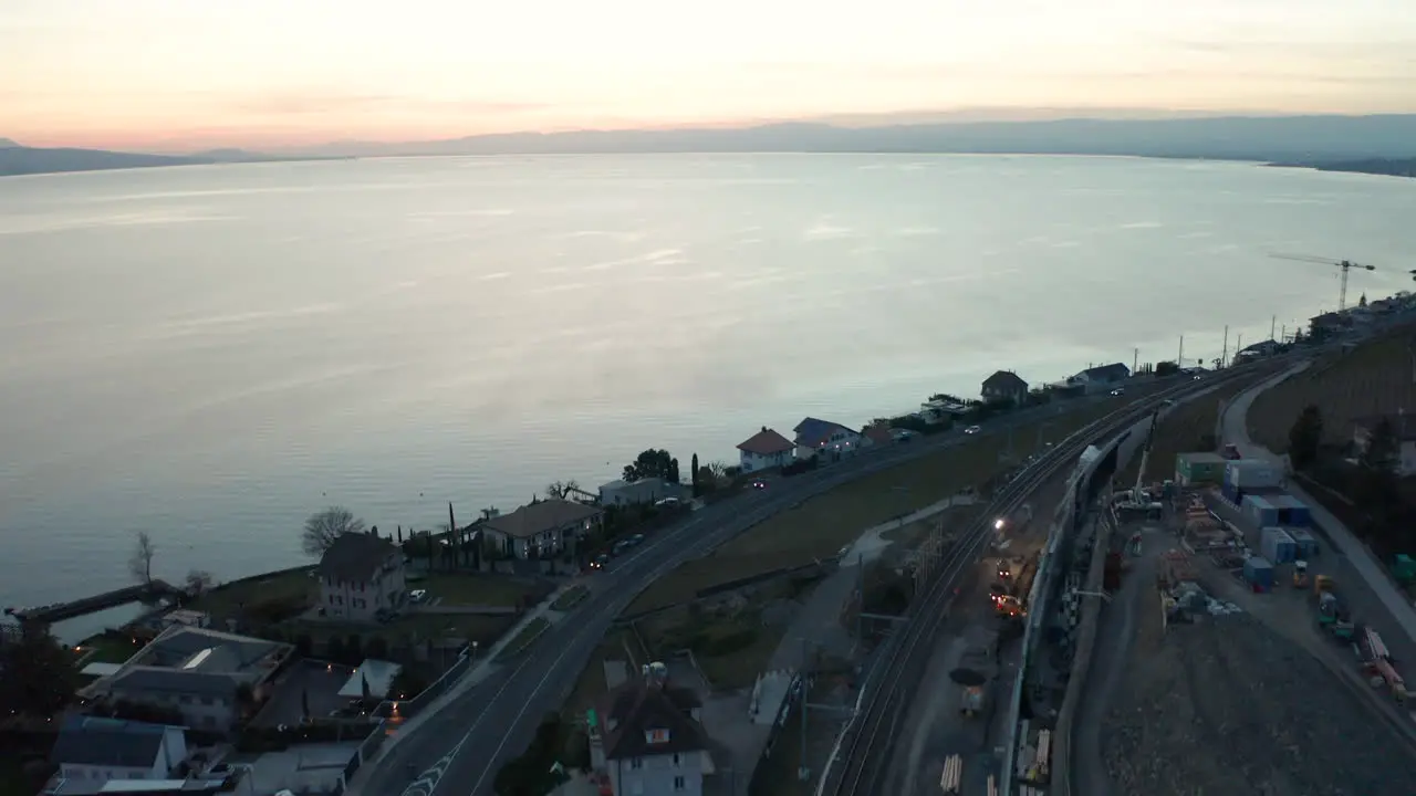 Aerial of small town under construction near large lake at sunset