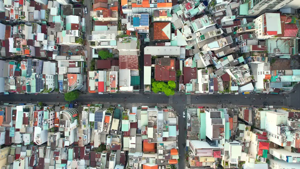 aerial top down shot of a perpendicular road intersection in a densely populated asian city in the afternoon as motorbikes drive through the narrow roads in Ho Chi Minh City Vietnam