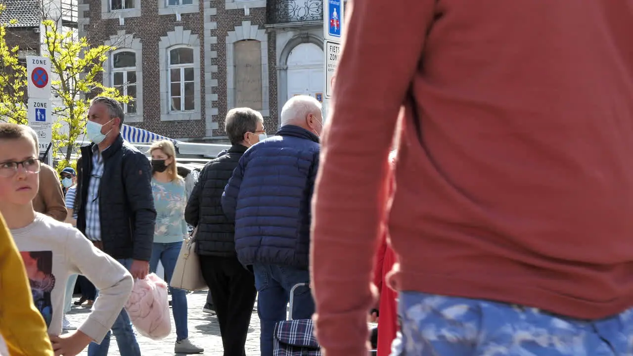 People with face masks walking at city market in Tongeren