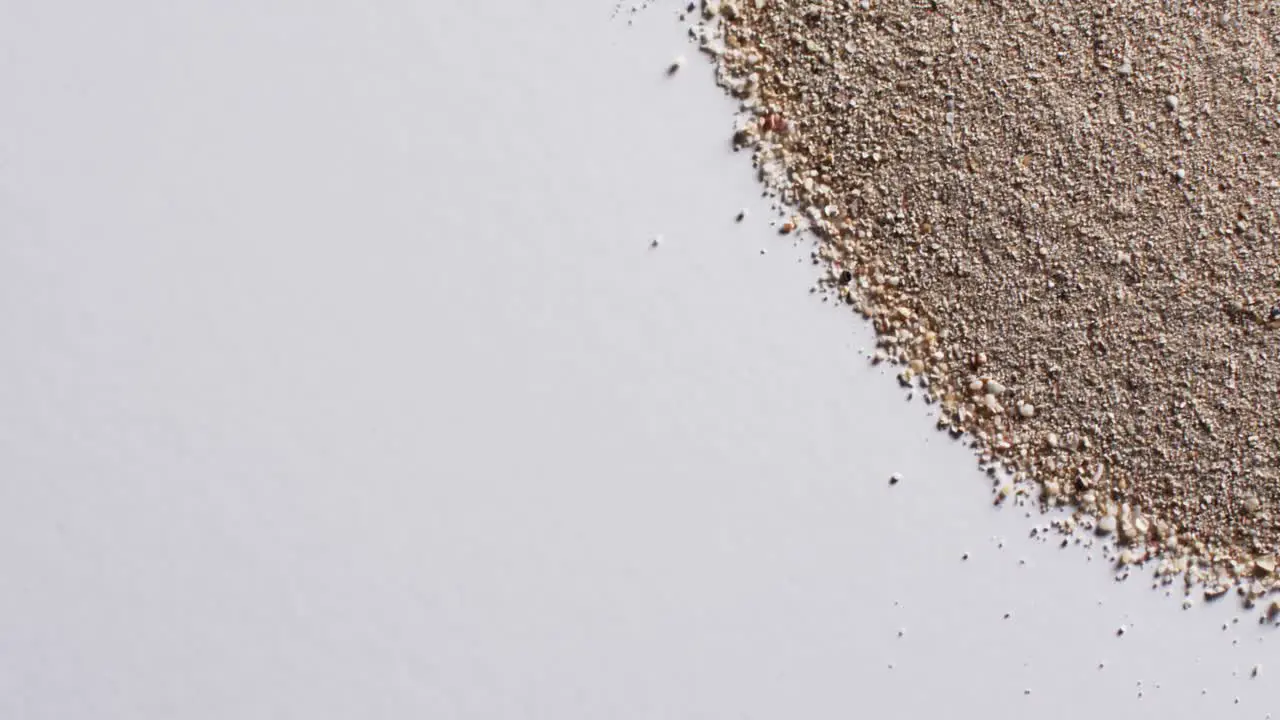 Video of close up of heap of sand grains and copy space on white background