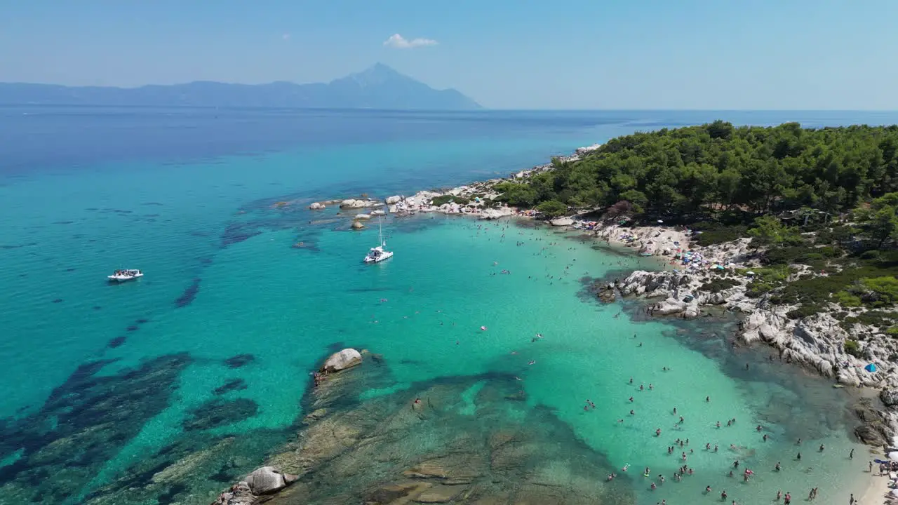 People Swim in Clear Blue Sea at Orange Beach Bay in Halkidiki Greece Aerial 4k