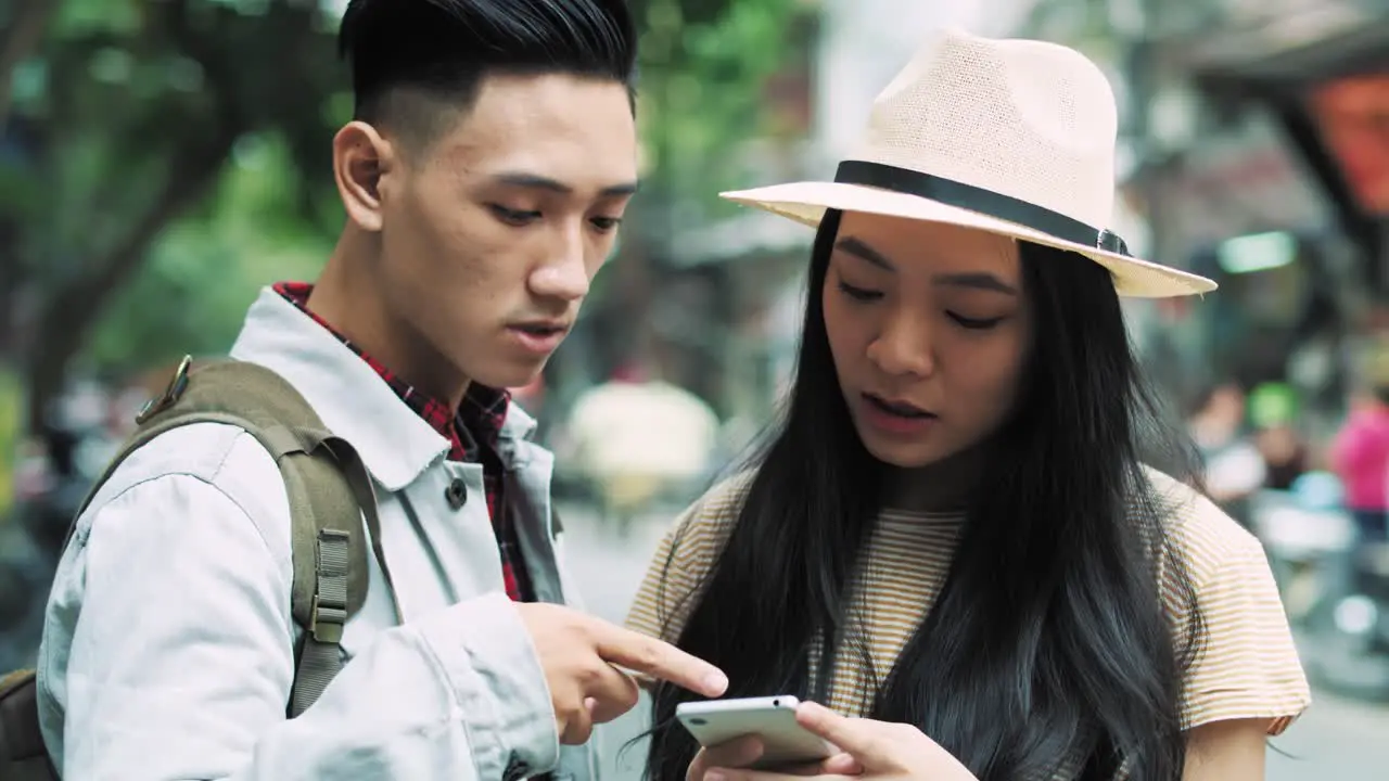 Handheld view of Vietnamese couple of tourists choosing the best path for travel