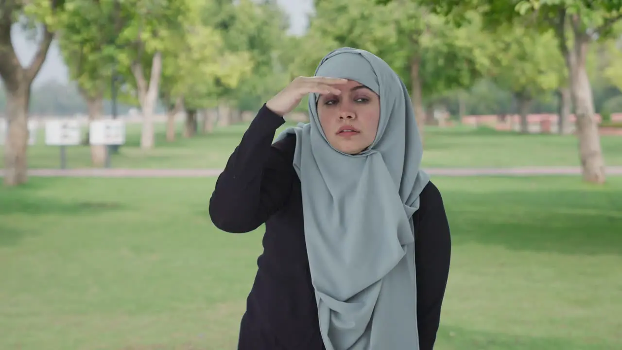 Confused Muslim woman searching for someone in park