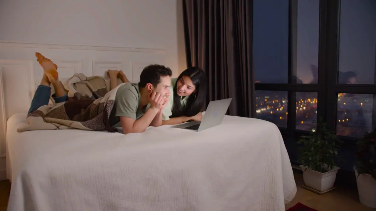 Couple Watching Interesting Movie On Latop Lying In Bed At Home