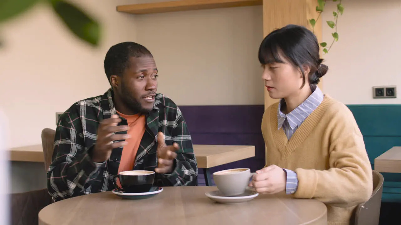 Man And Woman Talking Together While Sitting At Table In A Coffee Shop 1