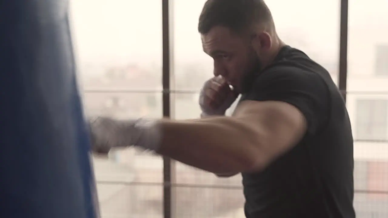 Alone boxer is hitting punching bag very fast in the fitness studio