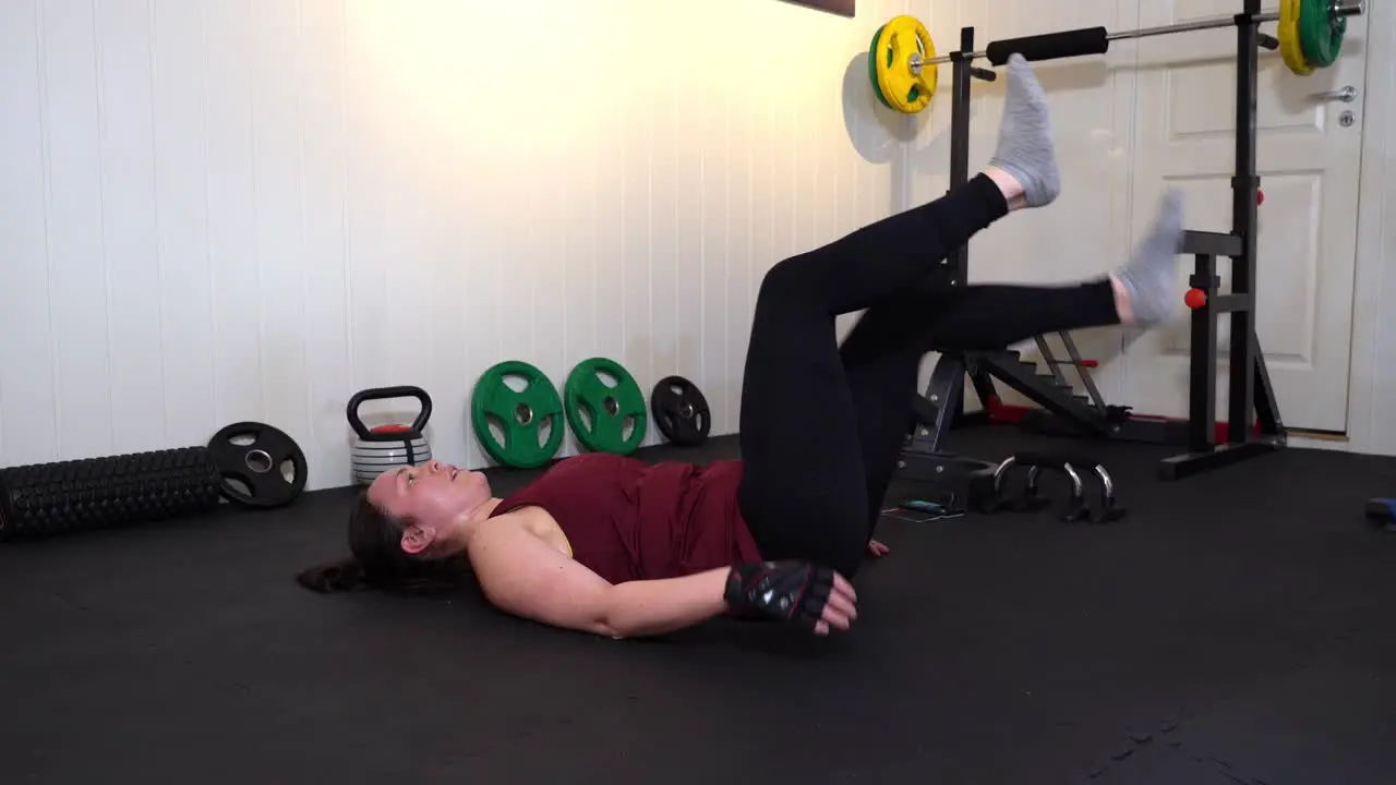 Leg strength exercise performed by happy smiling woman in small gymnasium