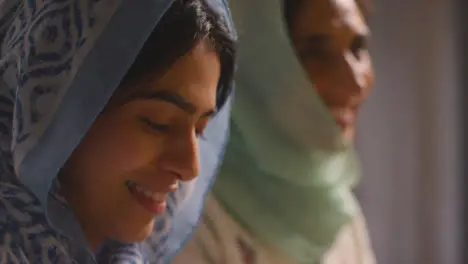 Muslim Mother And Daughter Sitting Around Table At Home Eating Meal Together