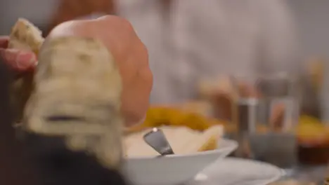 Close Up Of Muslim Muslim Family Sitting Around Table At Home Eating Meal To Celebrate Eid